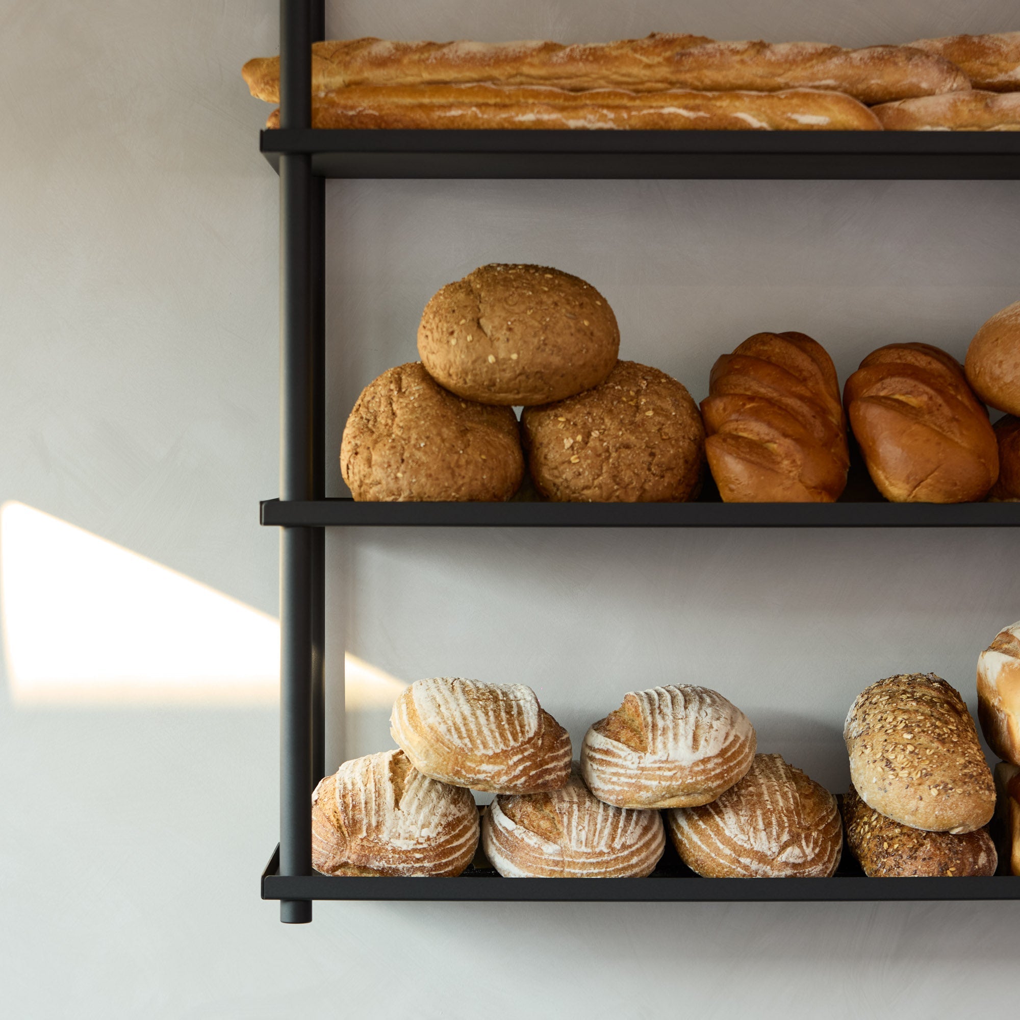 closer up of black ceiling mounted shelves displaying bread at a bakery