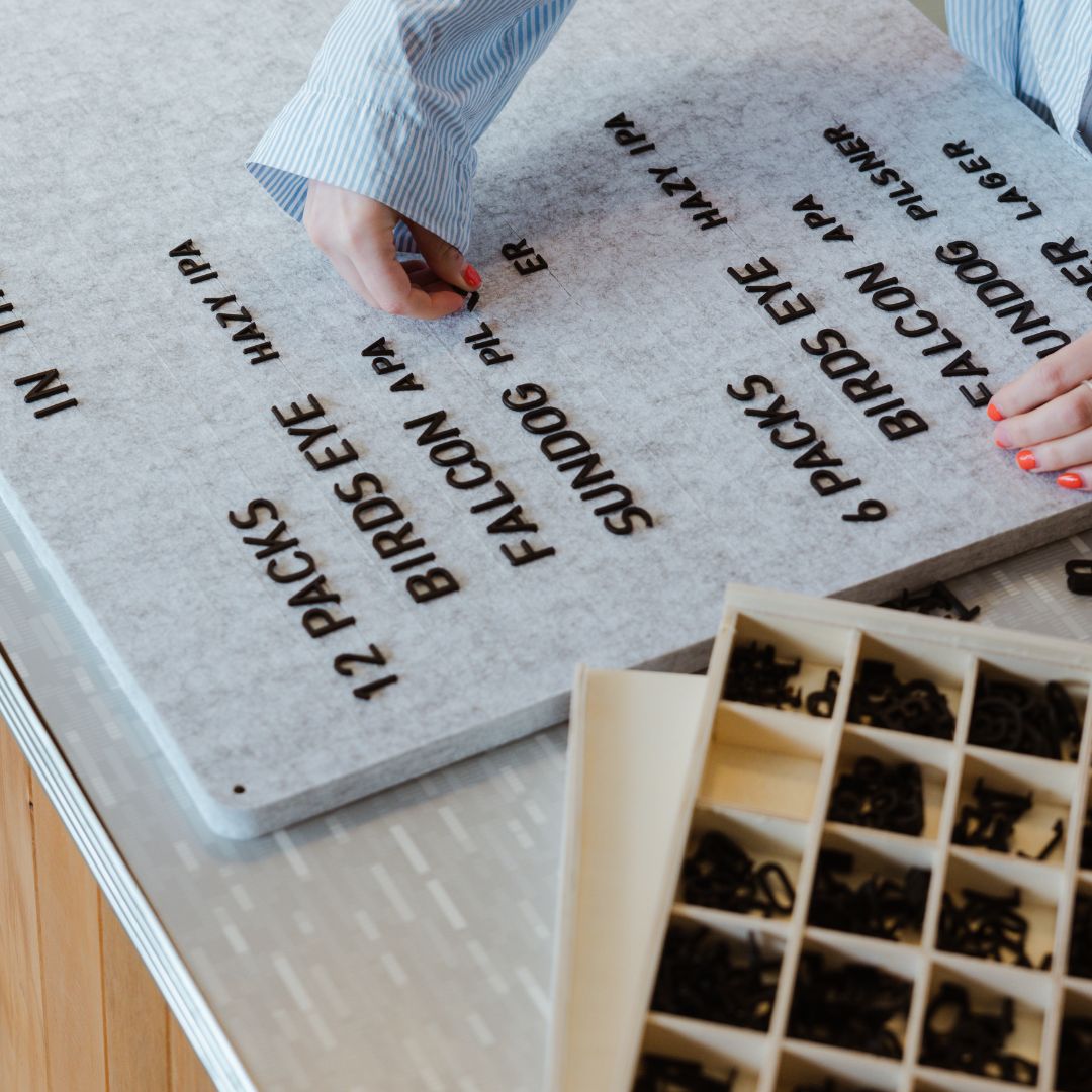 person putting black felt board letters into their felt menu display