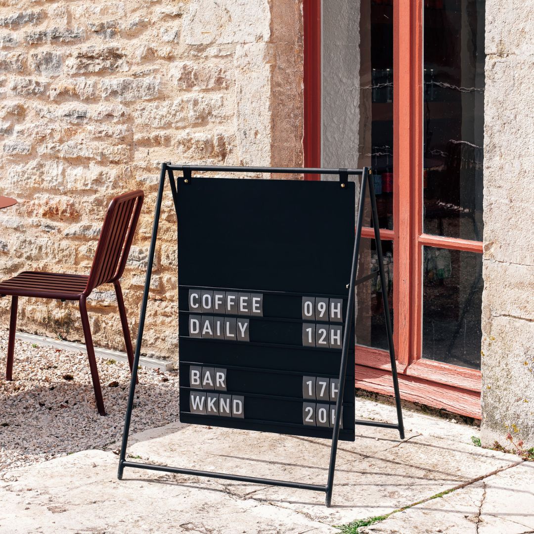 black large letter sidewalk sandwich board sign in front of a storefront facade