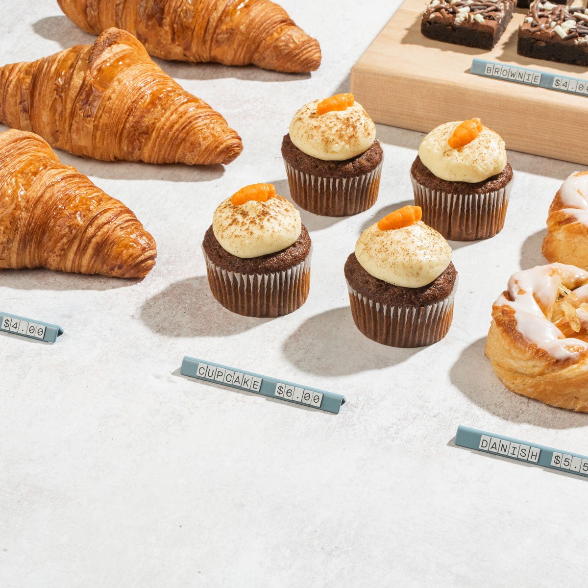 white large pricing signs in front of small cakes and pastries