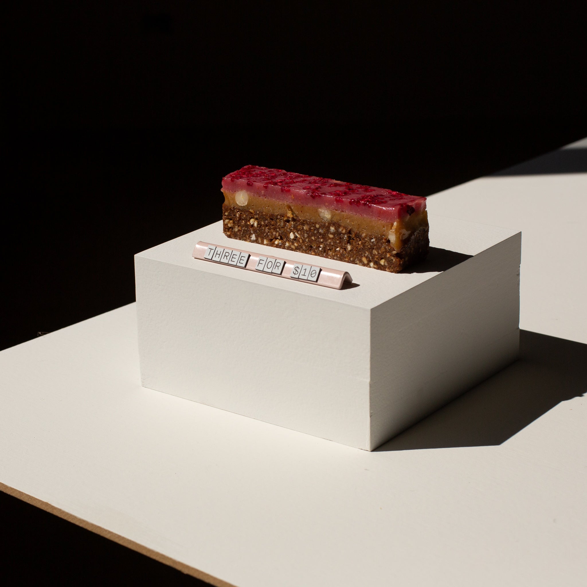 large pricing sign on an elevated display box in front of a cake