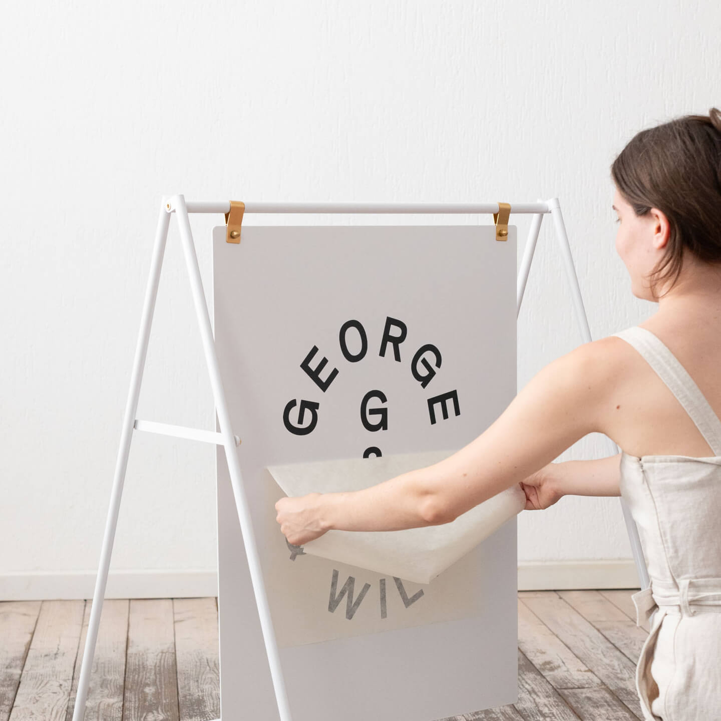 white large sidewalk sign inside a studio with person applying vinyl to the face plate