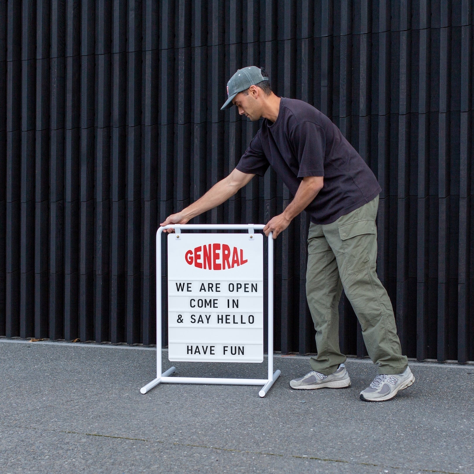 person putting out the white letter swing sandwich board sign on a footpath