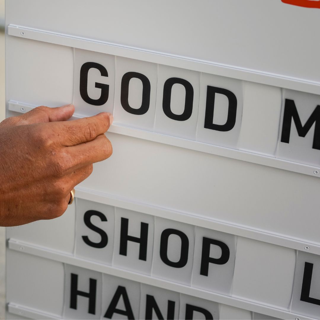 close up of hand adjusting pop in letters of the sandwich board letter swing sign
