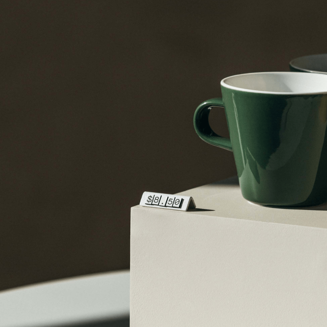white pricing tag in front of green coffee cup