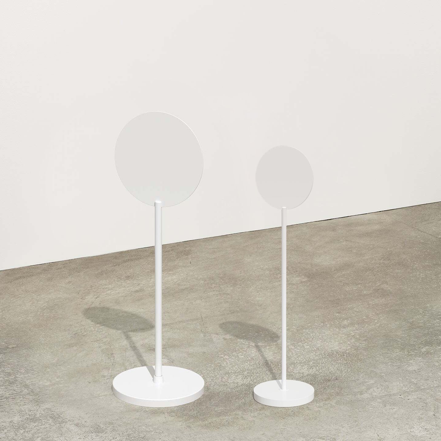 two sizes of white standing round sign side by side in studio