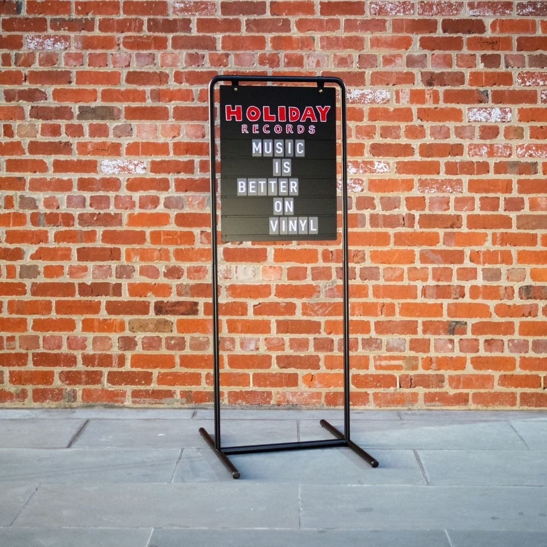 black tall letter swing business sign against a brick facade