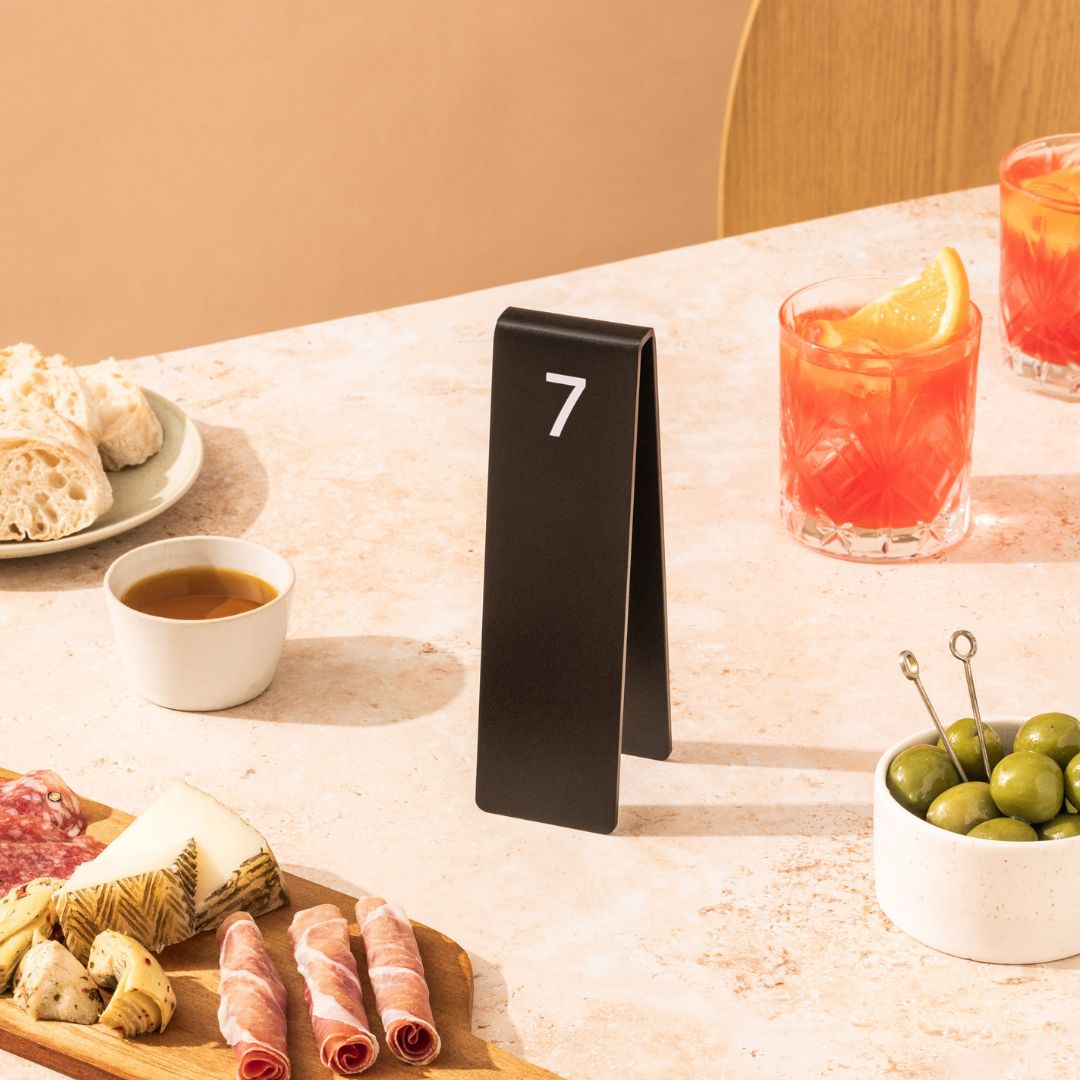 Black table number stacker on restaurant table beside croissant and iced drink