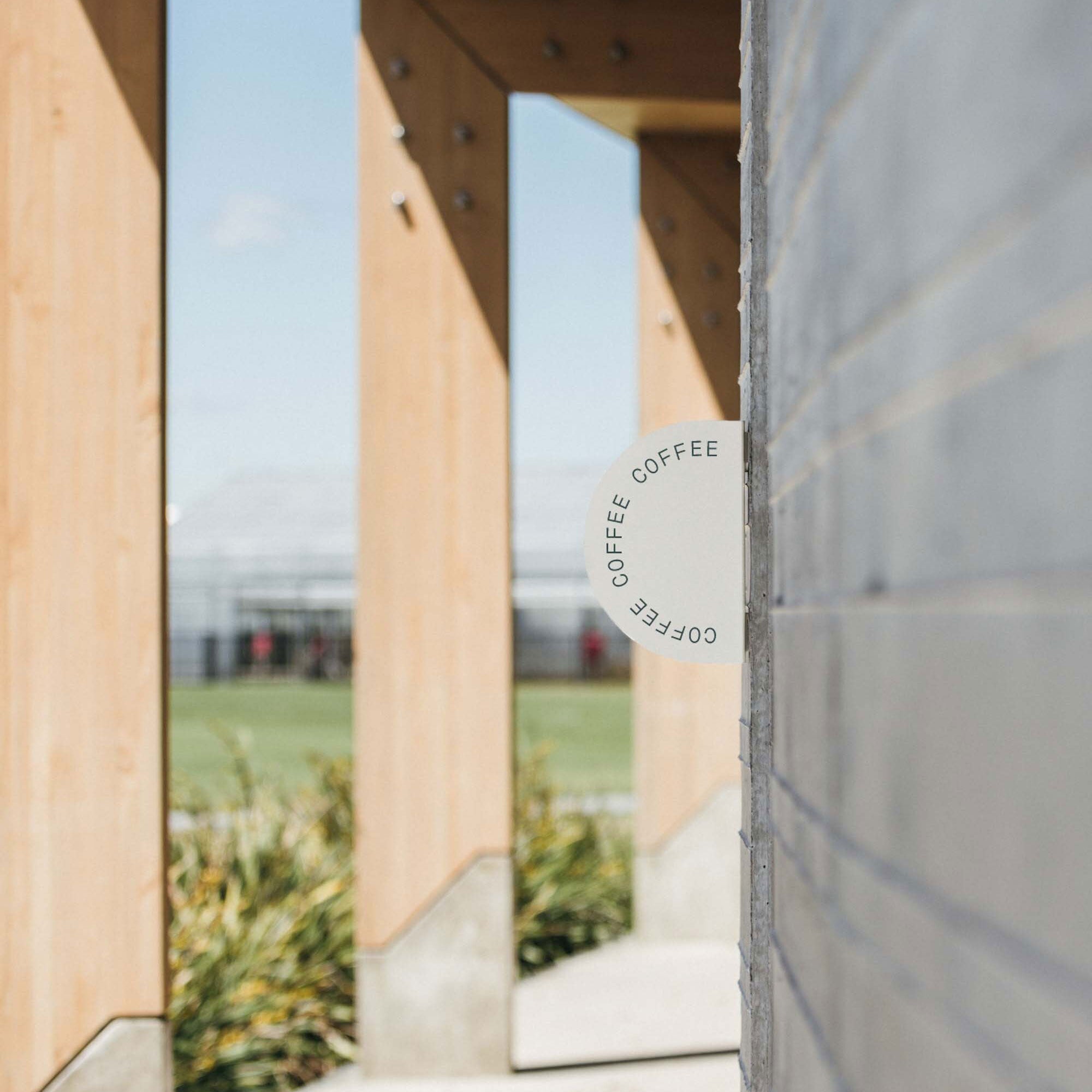 oat coloured half round blade sign installed on concrete wall outside in a sidewalk