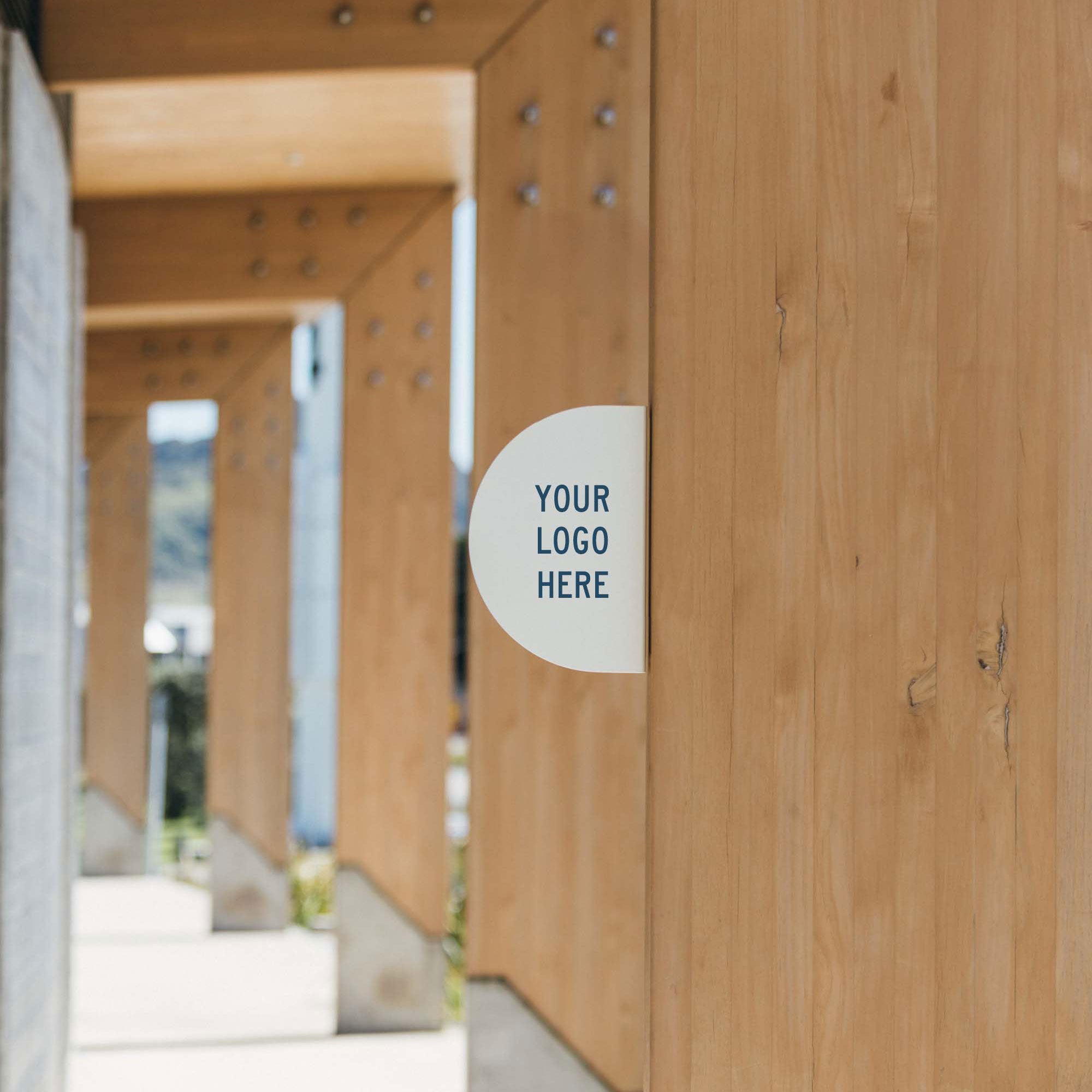 white half round blade sign installed in wood in an outdoor corridor