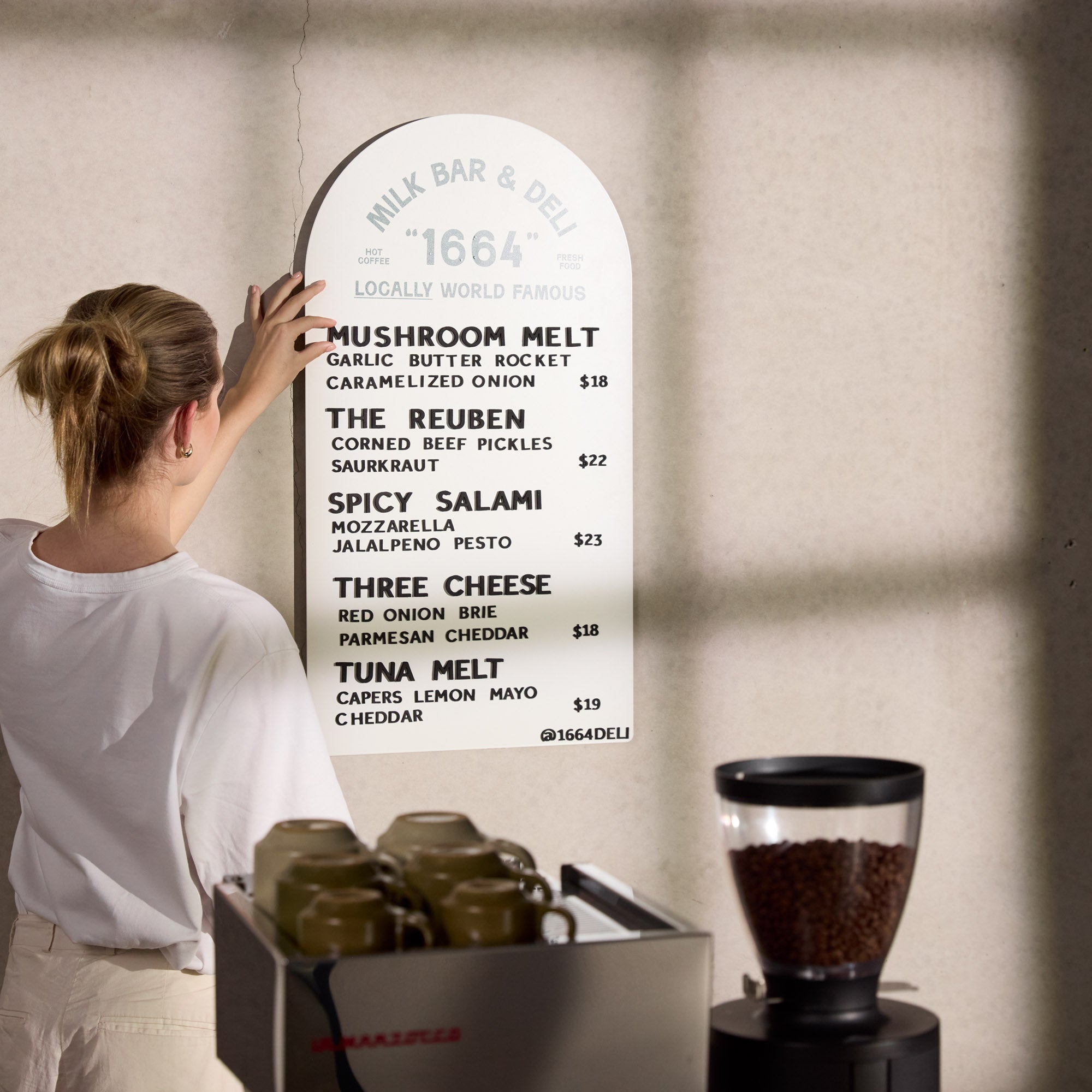 white arch menu display installed wall-mounted with girl adjusting magnet letters