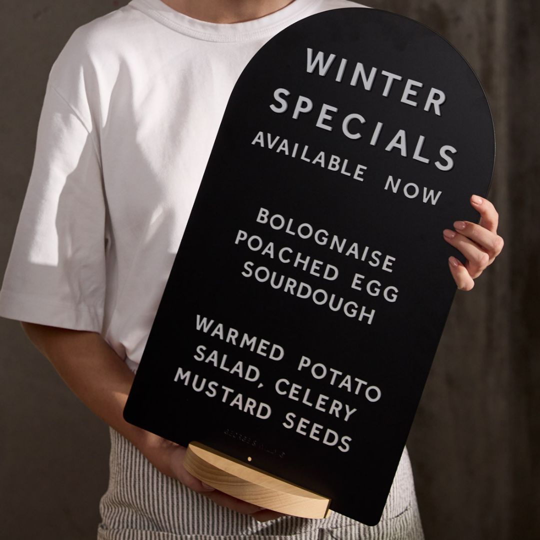 close up of girl carrying arch tabletop sign on an angle including the wooden base