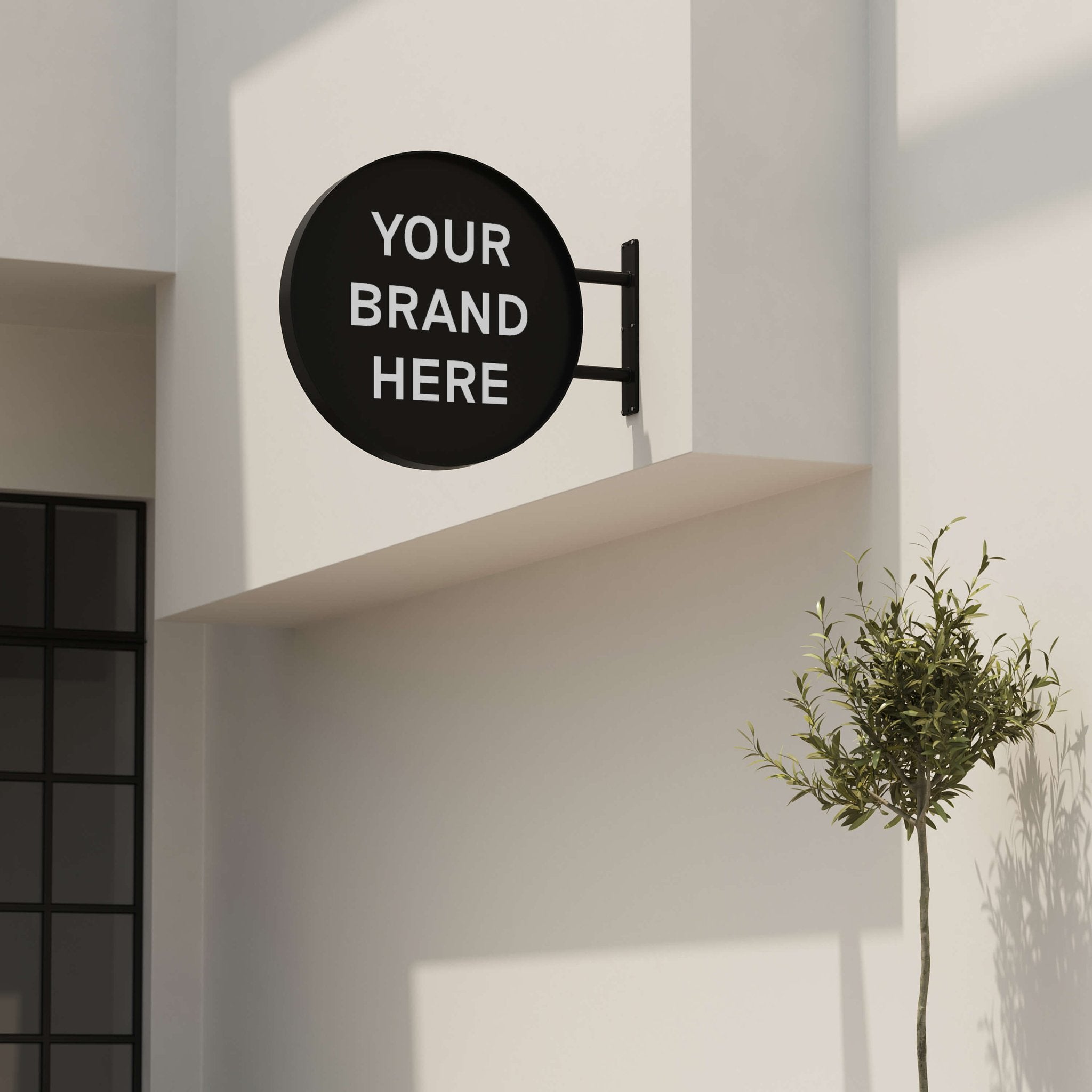 Black round wall sign for café branding, mounted above storefront entrance and green plants