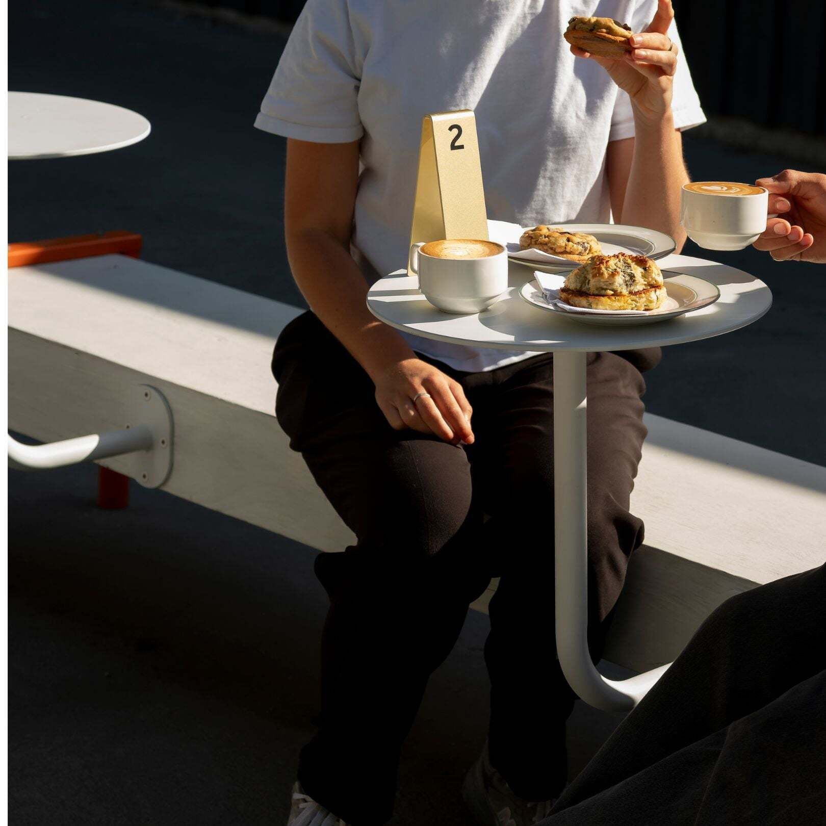 Customer seated at wall-mounted cafe table enjoying drink in outdoor restaurant seating