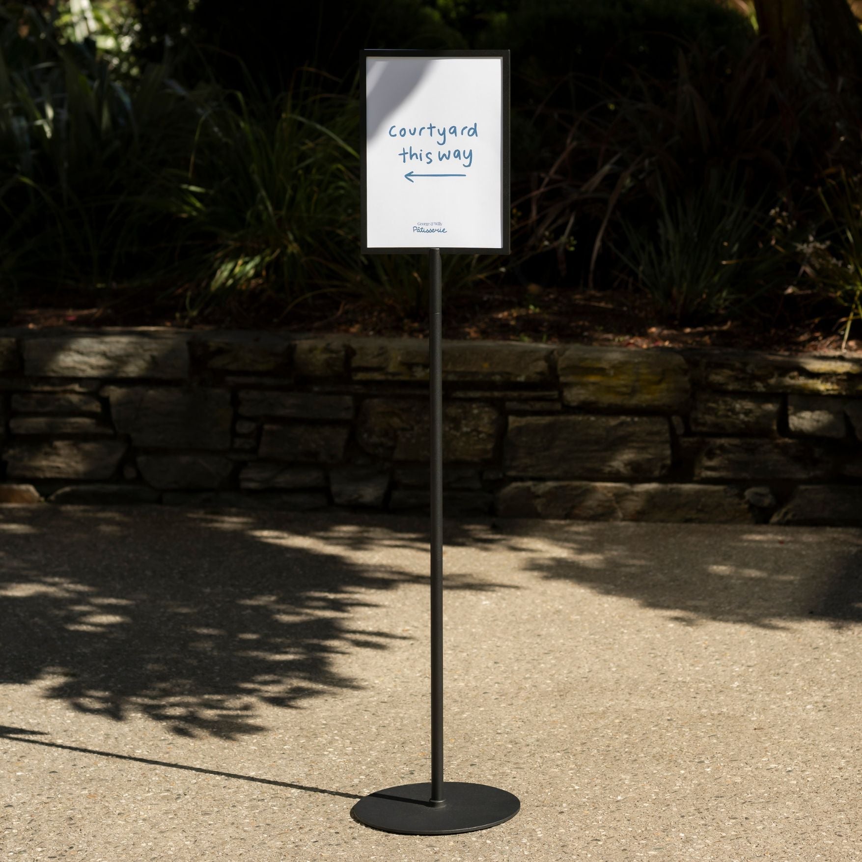black standing sign holder half in sun half in shade outside