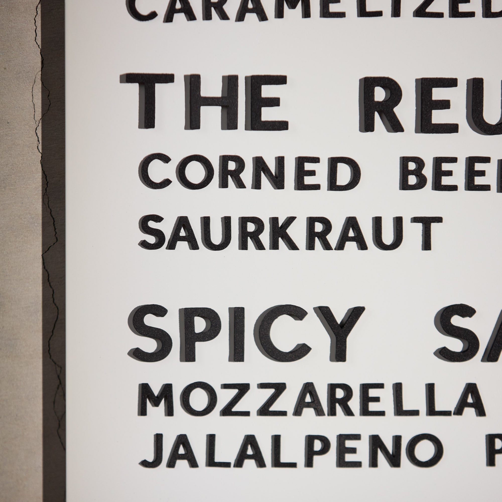 close up of black magnet letters on white arch menu display