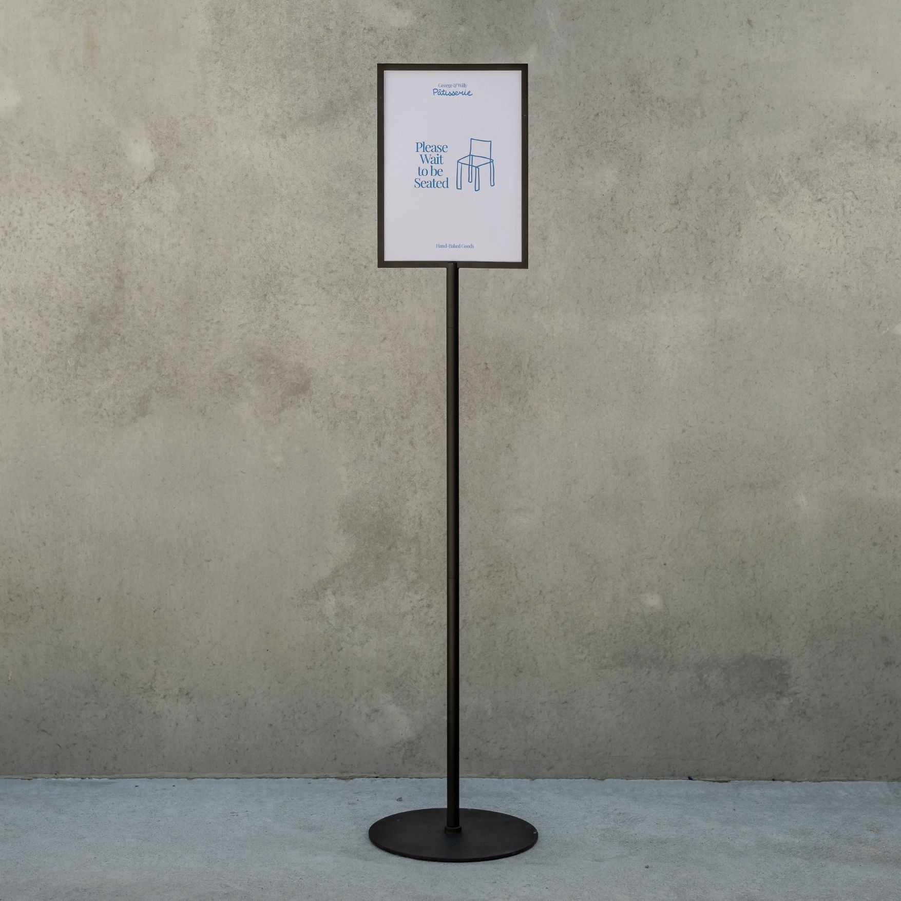 black freestanding sign holder in front of a concrete wall with small poster displayed