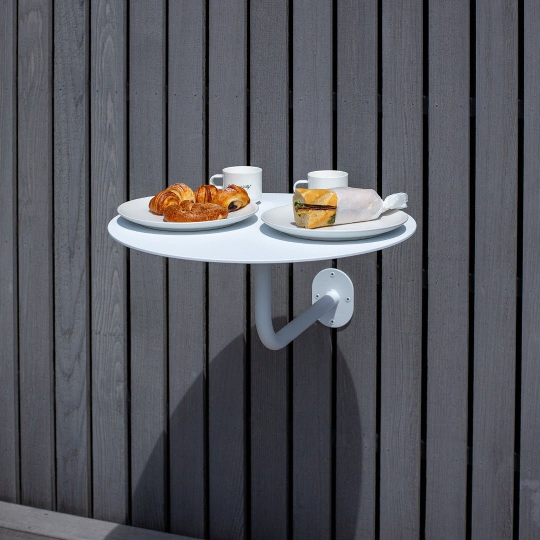 Large white bistro style cafe table mounted to wall holding restaurant table food