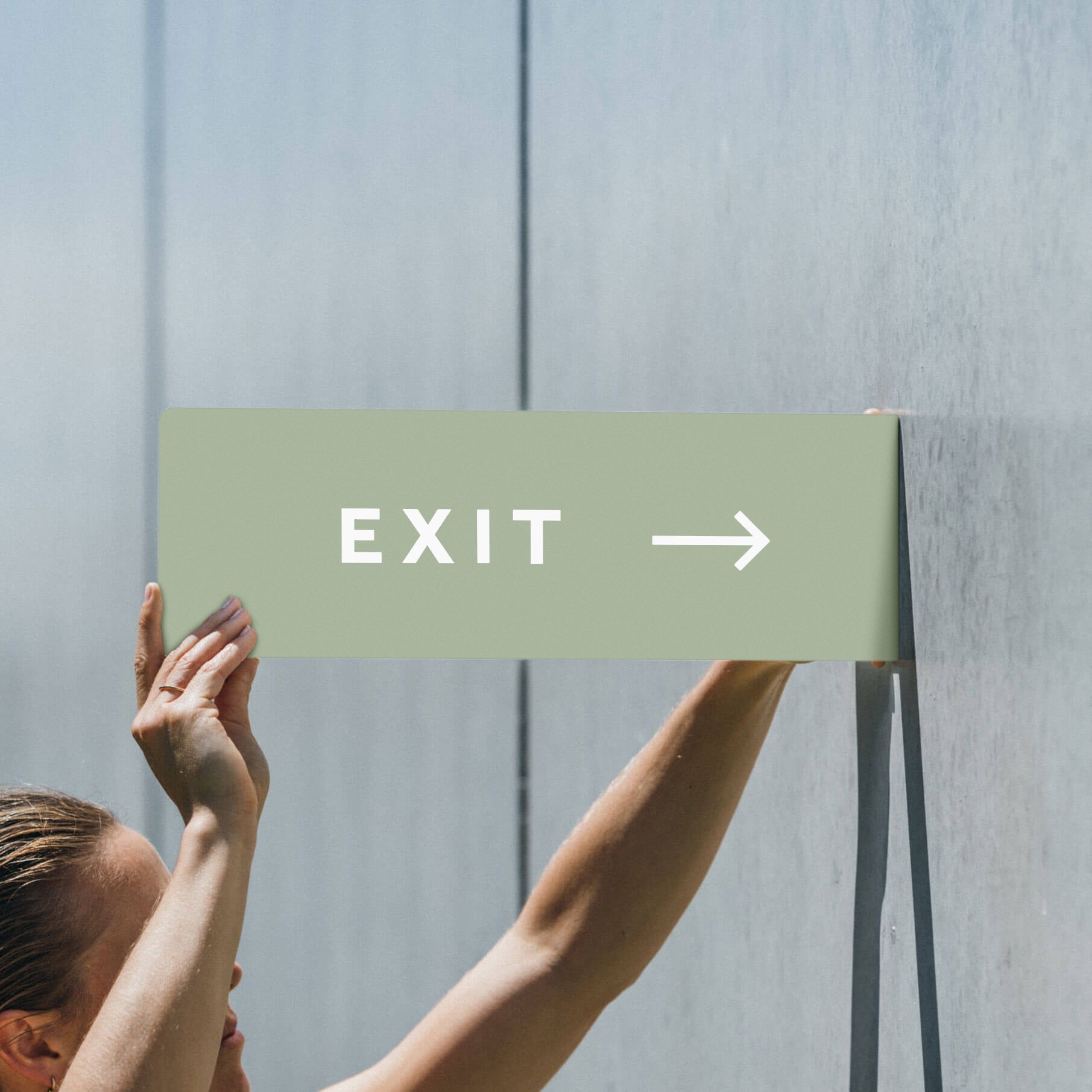 two hands holding up the sage green blade sign with "EXIT" on it