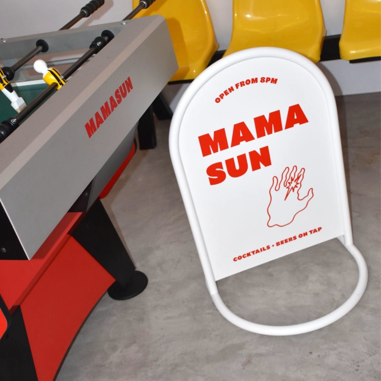 white rounded sidewalk business sign beside foosball machine with red logo branding applied