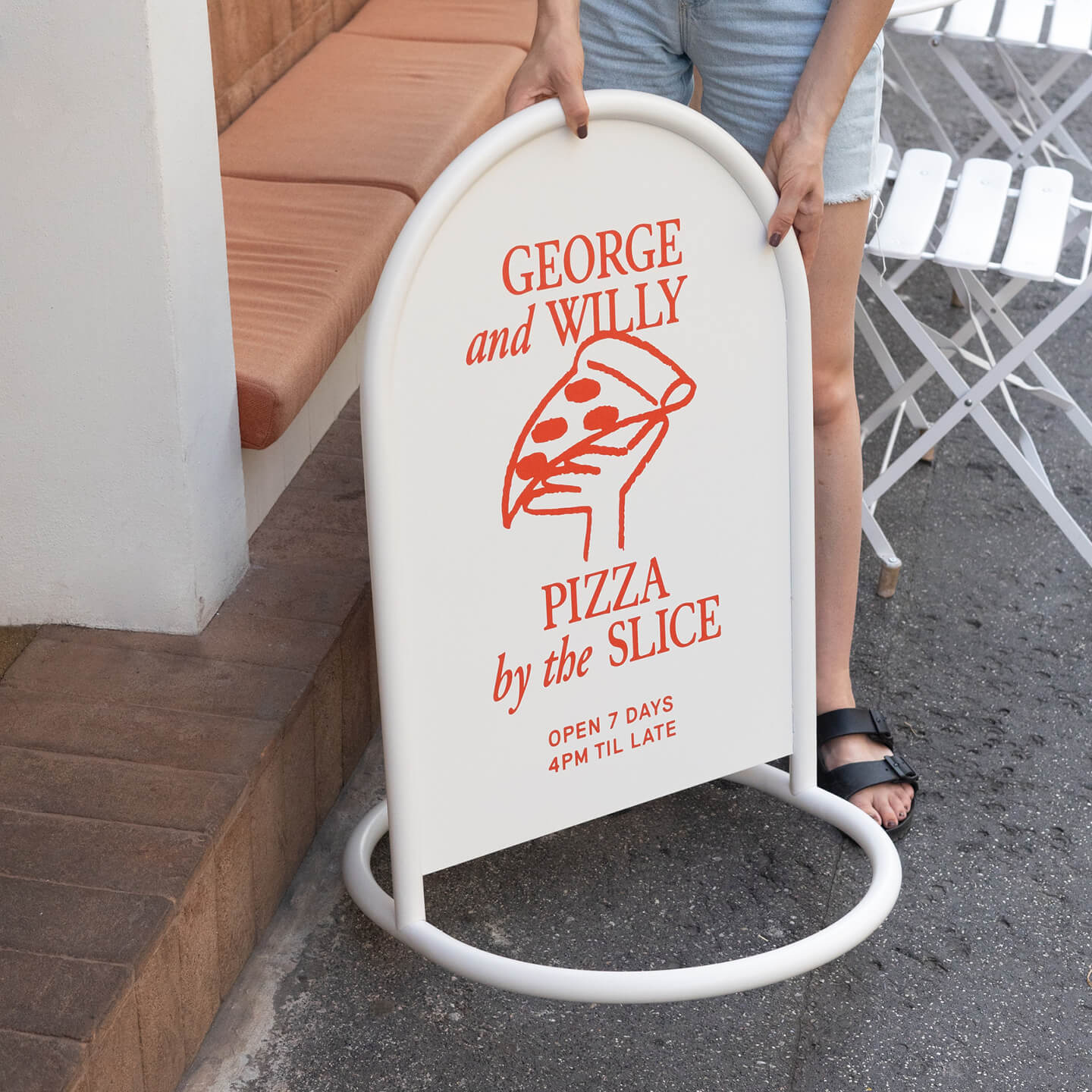 close up of a person lifting white rounded custom metal sign outside business