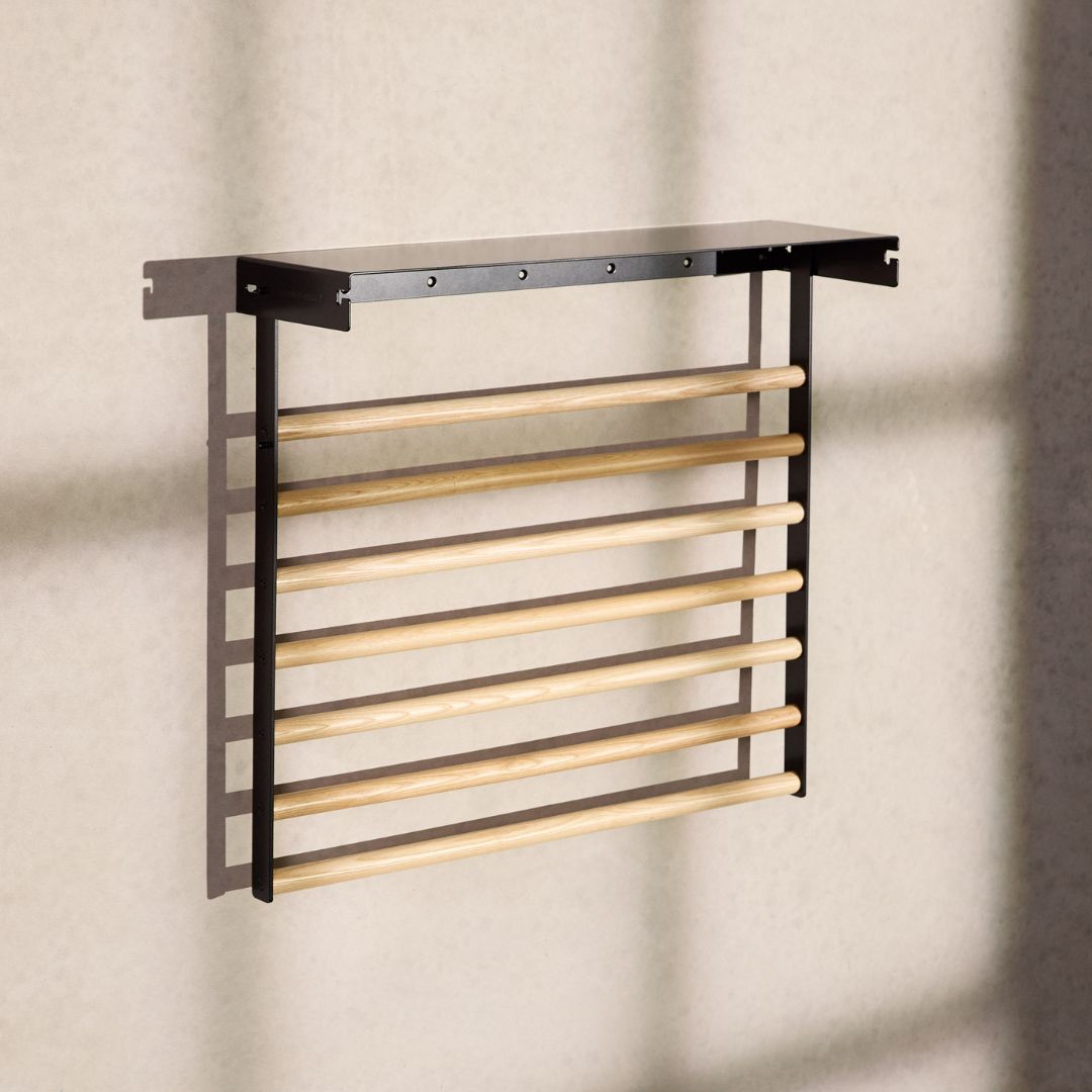 black wall mounted drying rack folded down with light shining through windows on it