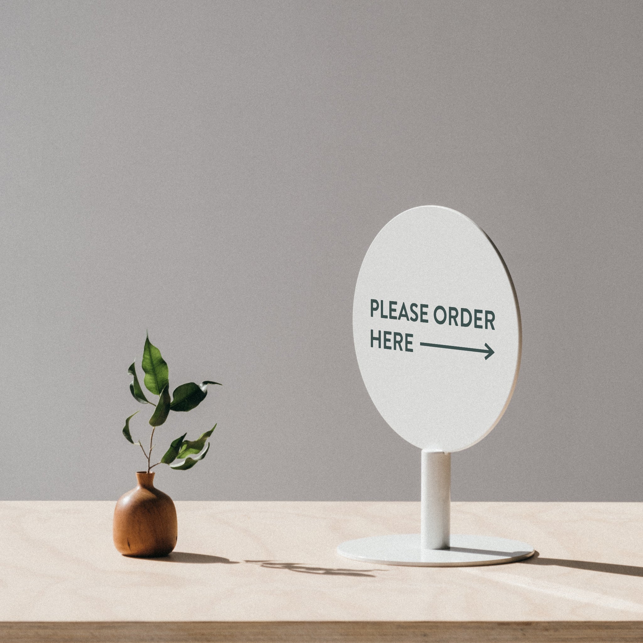 white circle sign on counter top next to a plant