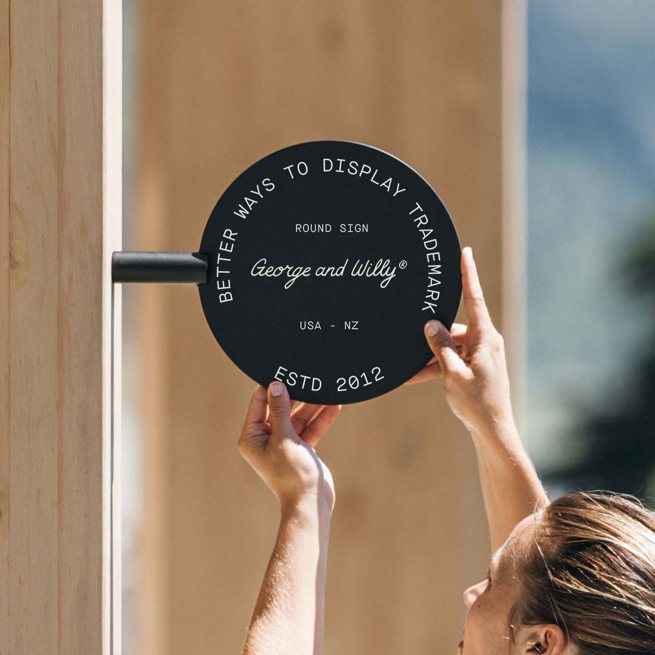 person holding the black circle sign up against a wooden beam to install