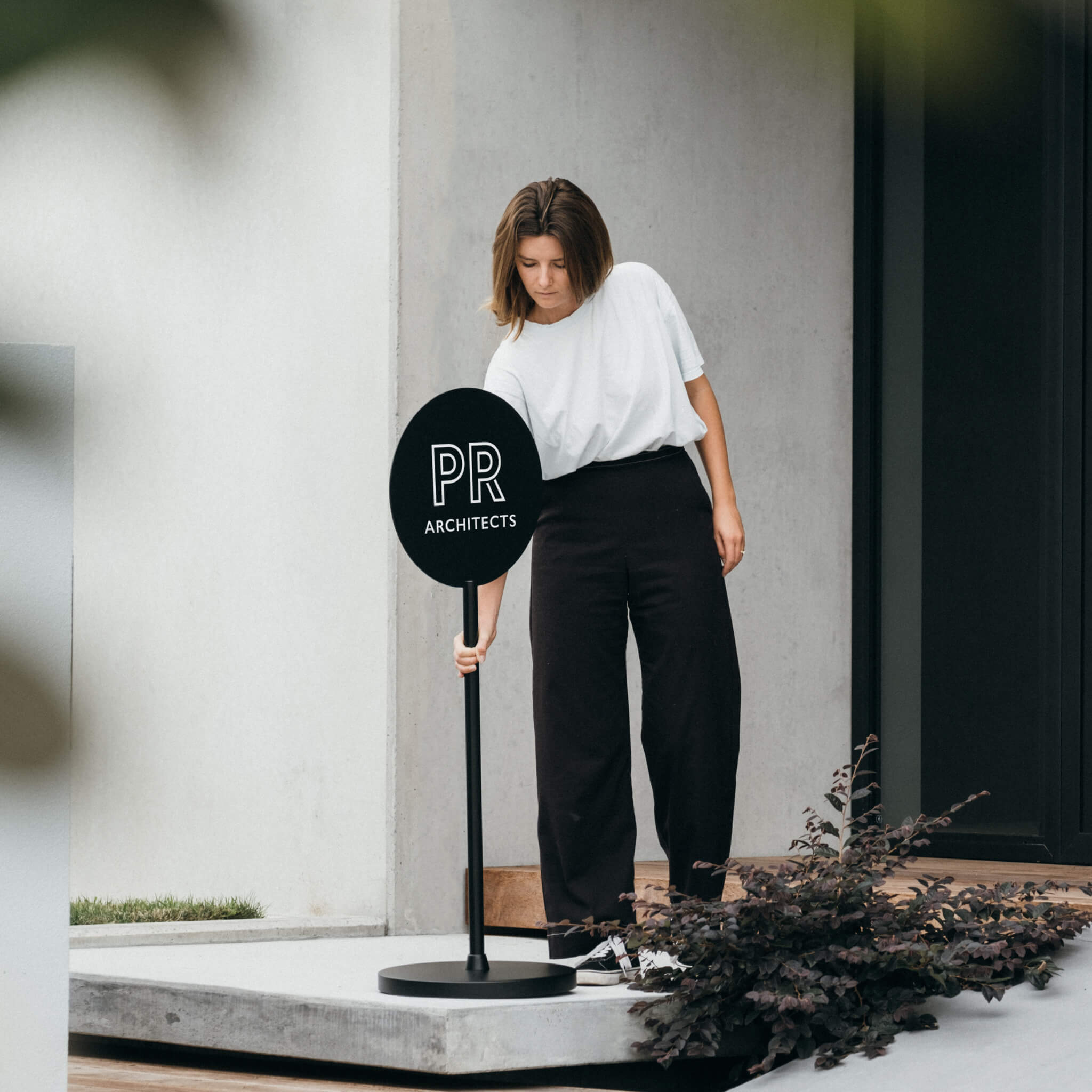 black metal standing round sign with logo being placed outside shopfront by person