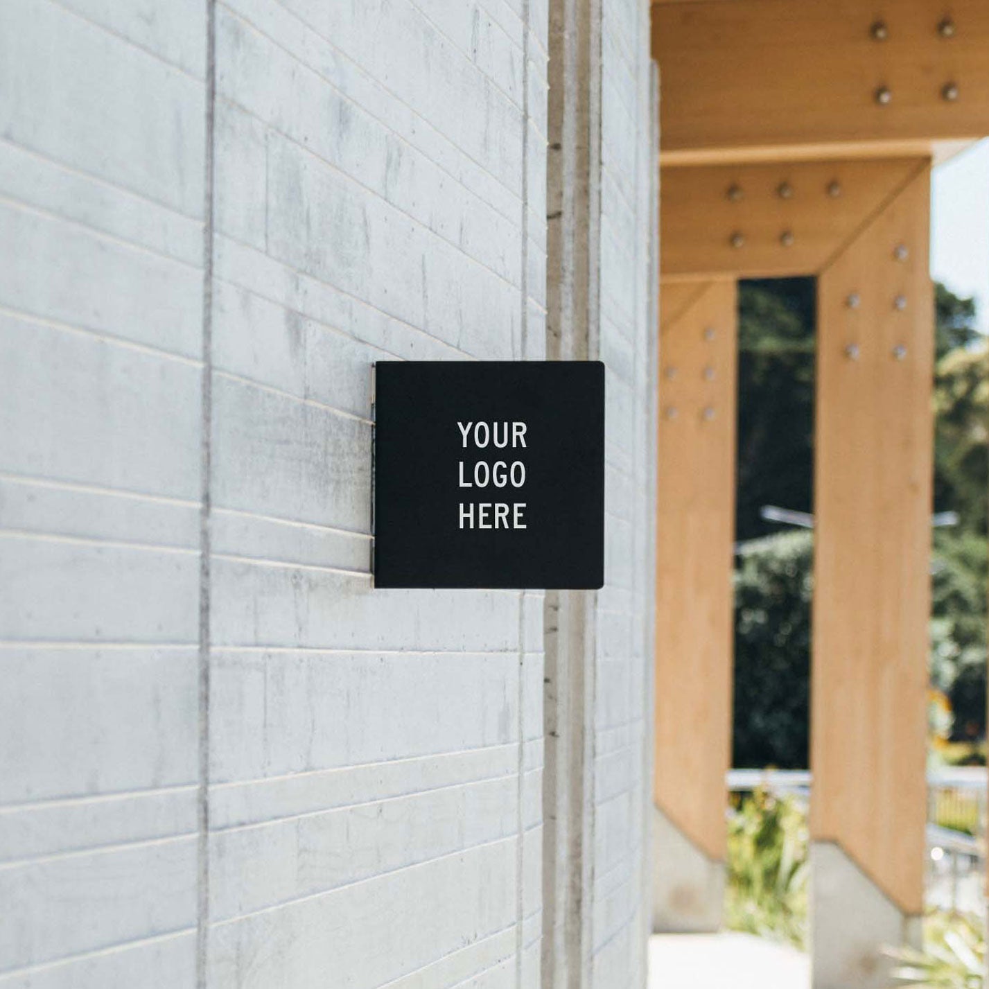 black square custom metal blade sign installed on cement wall